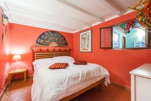 A room with a bed, a nightstand, a wall-mounted fan, and a painting.