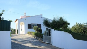 A white building with a gated entrance, cobblestone path, and a small garden area. - Large private villa, saltwater pool, great holiday in the Algarve (Carvoeiro)