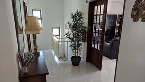 A hallway with a potted plant, a lamp, and a door leading to a living area. - Large private villa, saltwater pool, great holiday in the Algarve (Carvoeiro)
