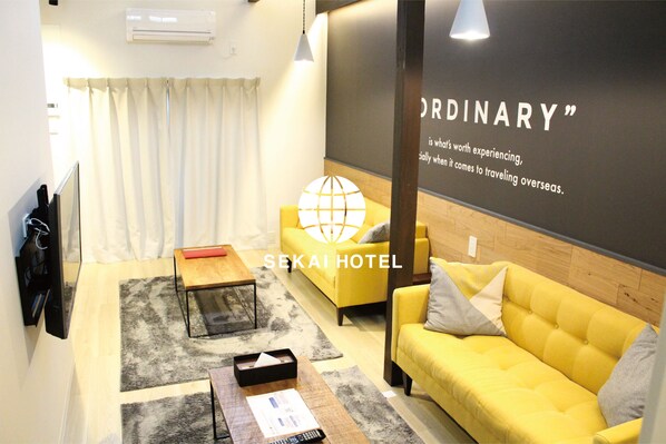 A modern hotel room with a yellow sofa, a wooden coffee table, and a globe decoration.