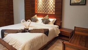 A neatly made bed with a decorative headboard, a wooden nightstand, and a framed butterfly painting on the wall. - Khum Sai Ngam Hotel & Resort (Songkhla)
