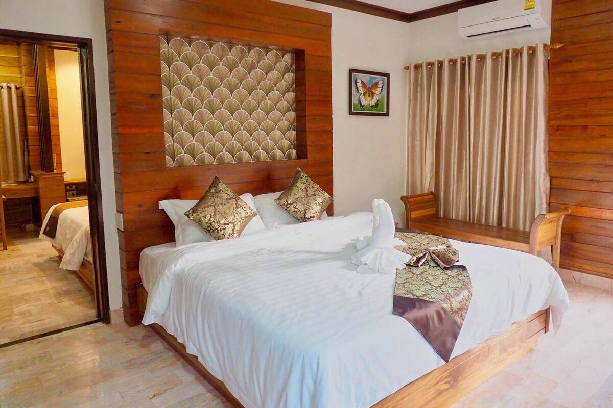 Une chambre d’hôtel avec un grand lit, une tête de lit en bois et une vue sur l’extérieur.