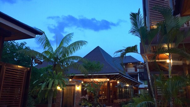 A resort with a covered outdoor area, palm trees, and a building with a sloped roof. - Khum Sai Ngam Hotel & Resort (Songkhla)