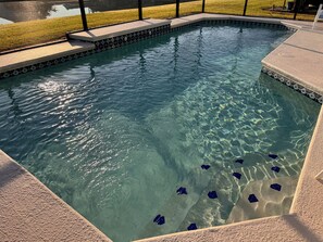 Ein klares Schwimmbecken mit geometrischen Fliesenmustern und einer umgebenden Sonnenterrasse.