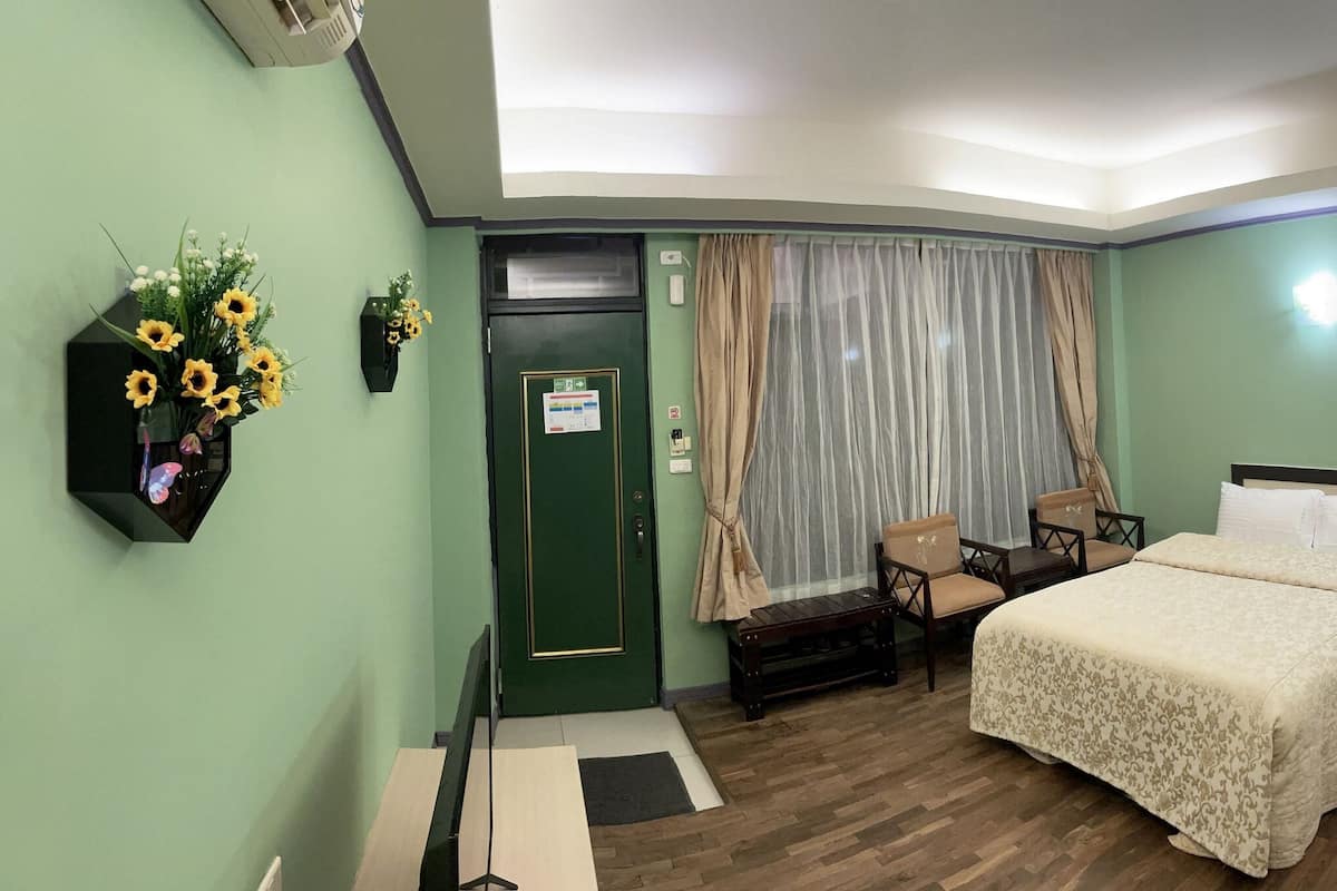 Une chambre d’hôtel avec deux lits, un bureau, une chaise, une petite table, un miroir, un lavabo et une porte.
