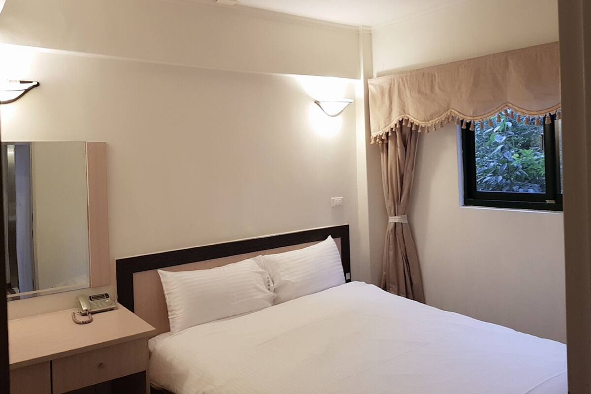 Une chambre d’hôtel avec un lit, une table de chevet et un miroir.
