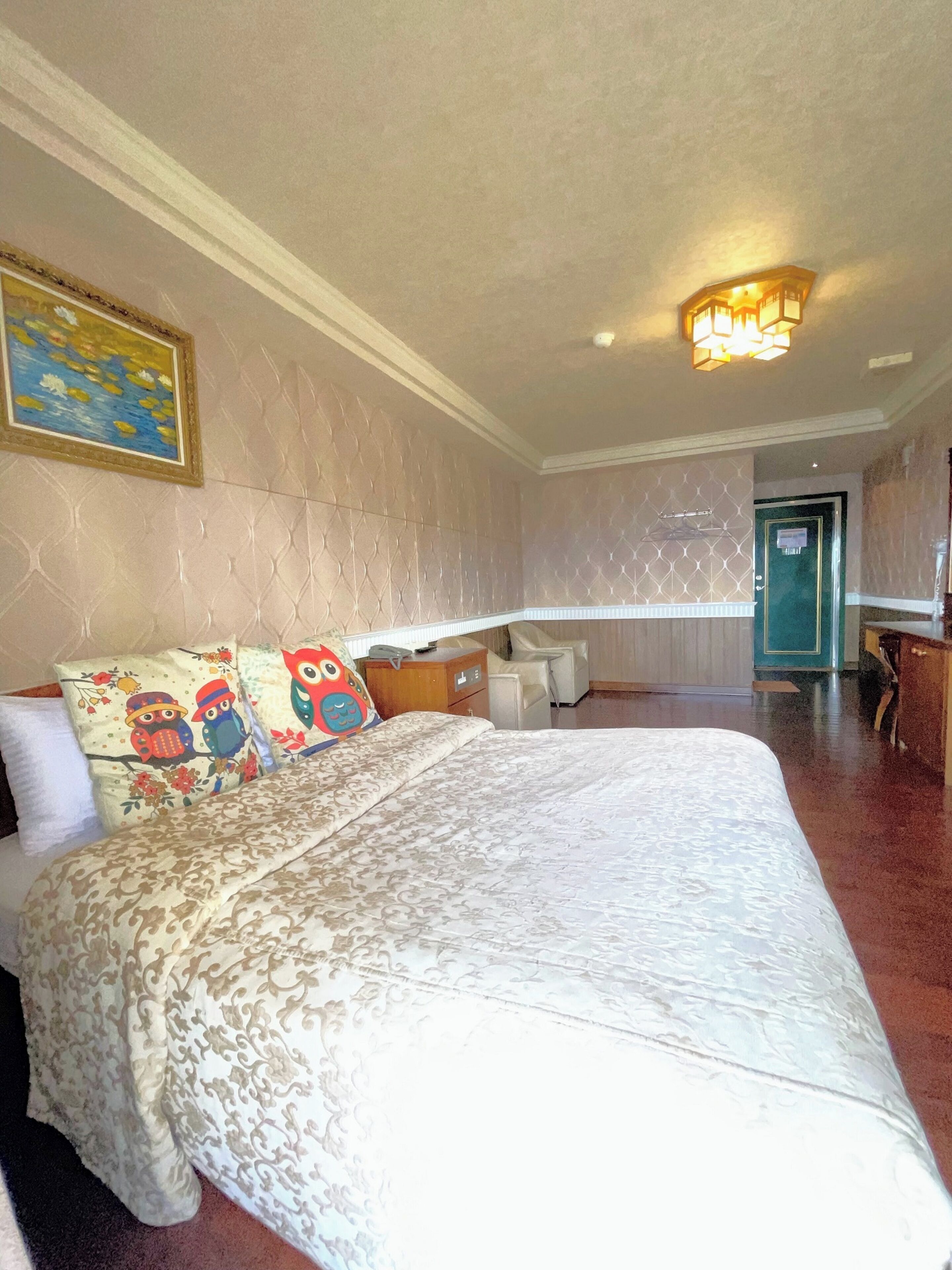 A hotel room with a large bed, a desk, and a chair.