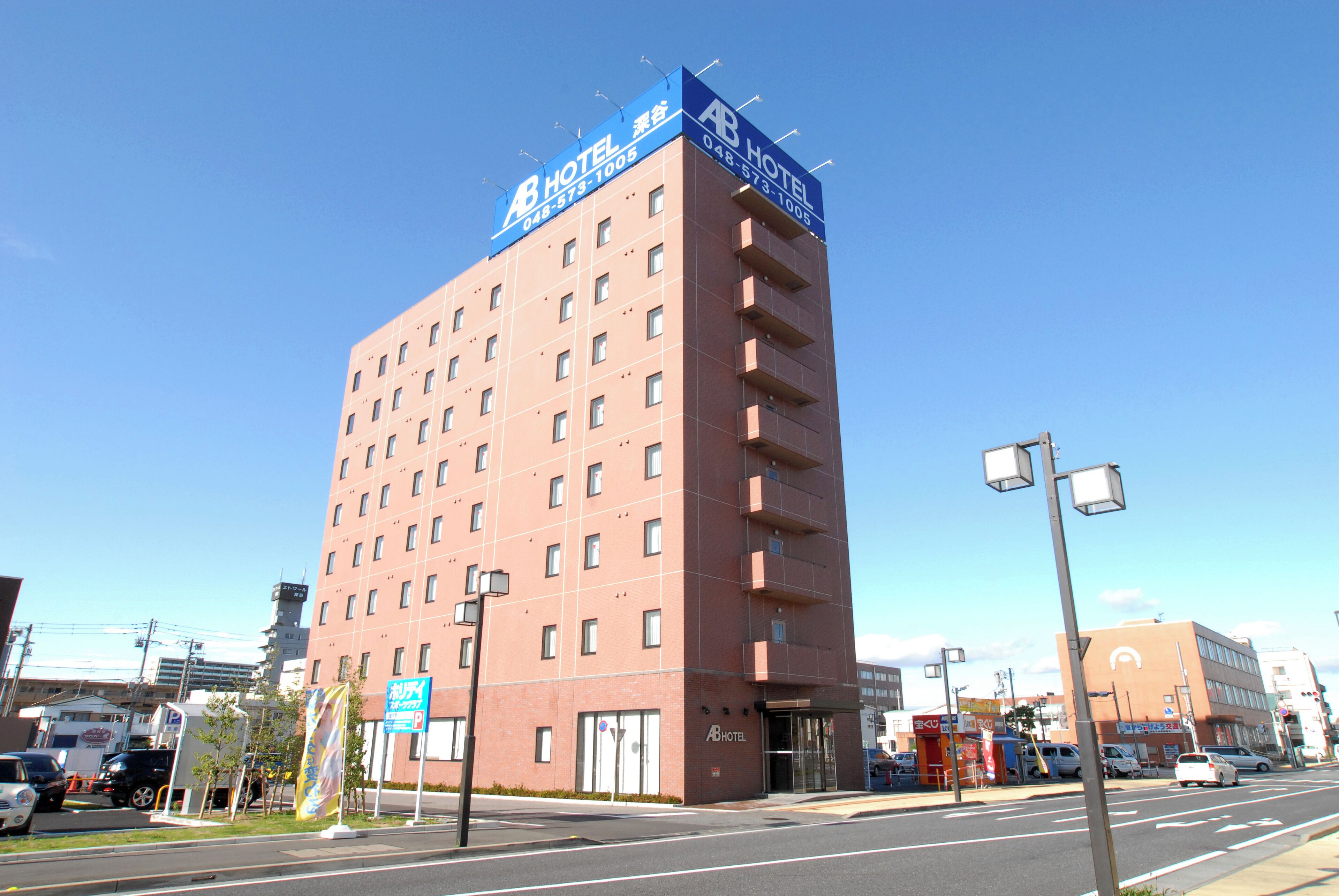 A multi-story hotel with a prominent blue sign on the top, multiple windows, and a parking sign visible.