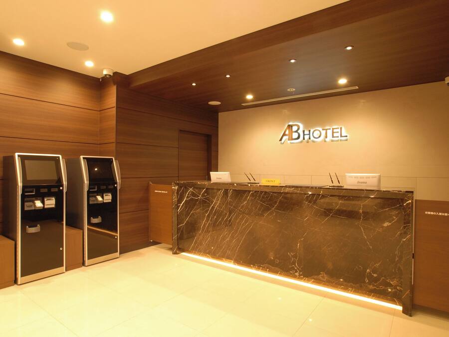 A hotel reception area with a marble counter, wooden paneling, and a reception desk.