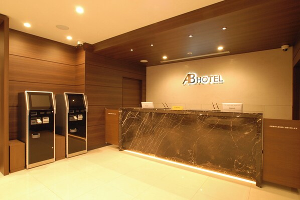 A hotel reception area with a marble counter, wooden paneling, and a reception desk.