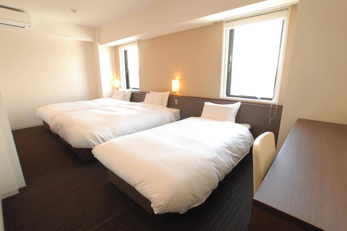 A hotel room with two single beds, a wooden desk, and two bedside lamps.