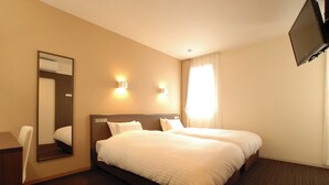 A hotel room with two beds, a desk, a chair, a TV, and a large mirror. - AB Hotel Fukaya (Fukaya)