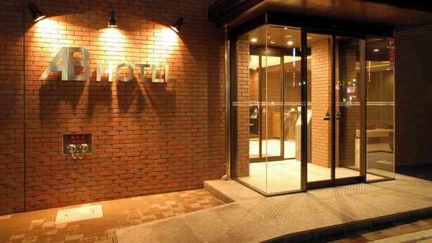 A hotel entrance with a brick facade, glass doors, and a sign reading "AB HOTEL". - AB Hotel Fukaya (Fukaya)