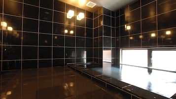 Una habitación moderna, con poca luz, que presenta un amplio suelo reflectante y un largo banco estrecho.