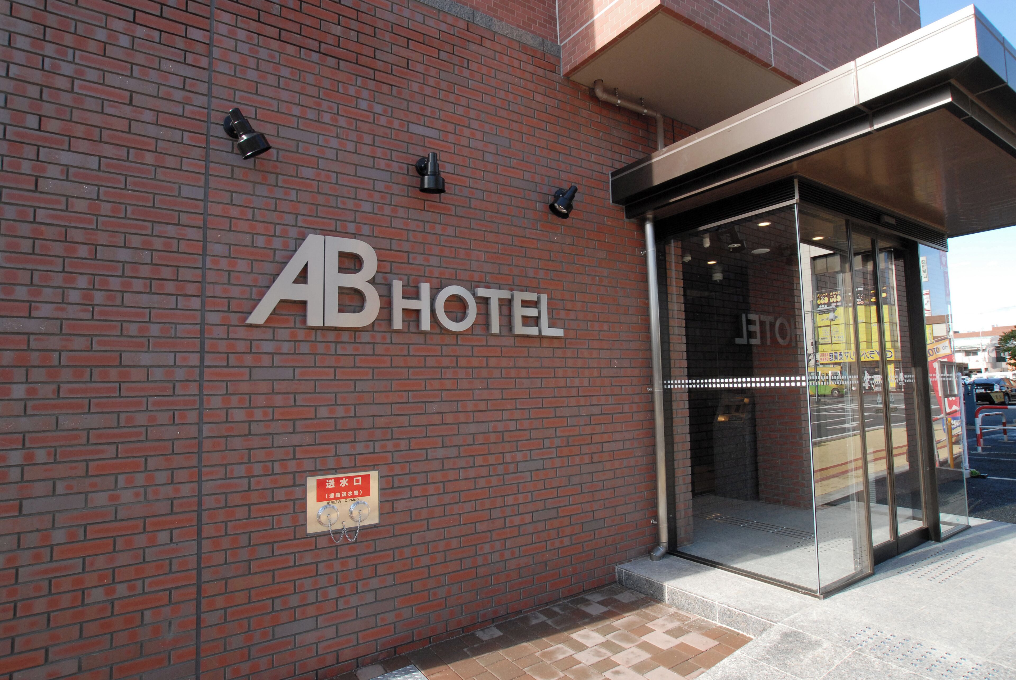 The exterior of AB Hotel with a brick facade, a glass entrance, and a sign indicating the entrance.