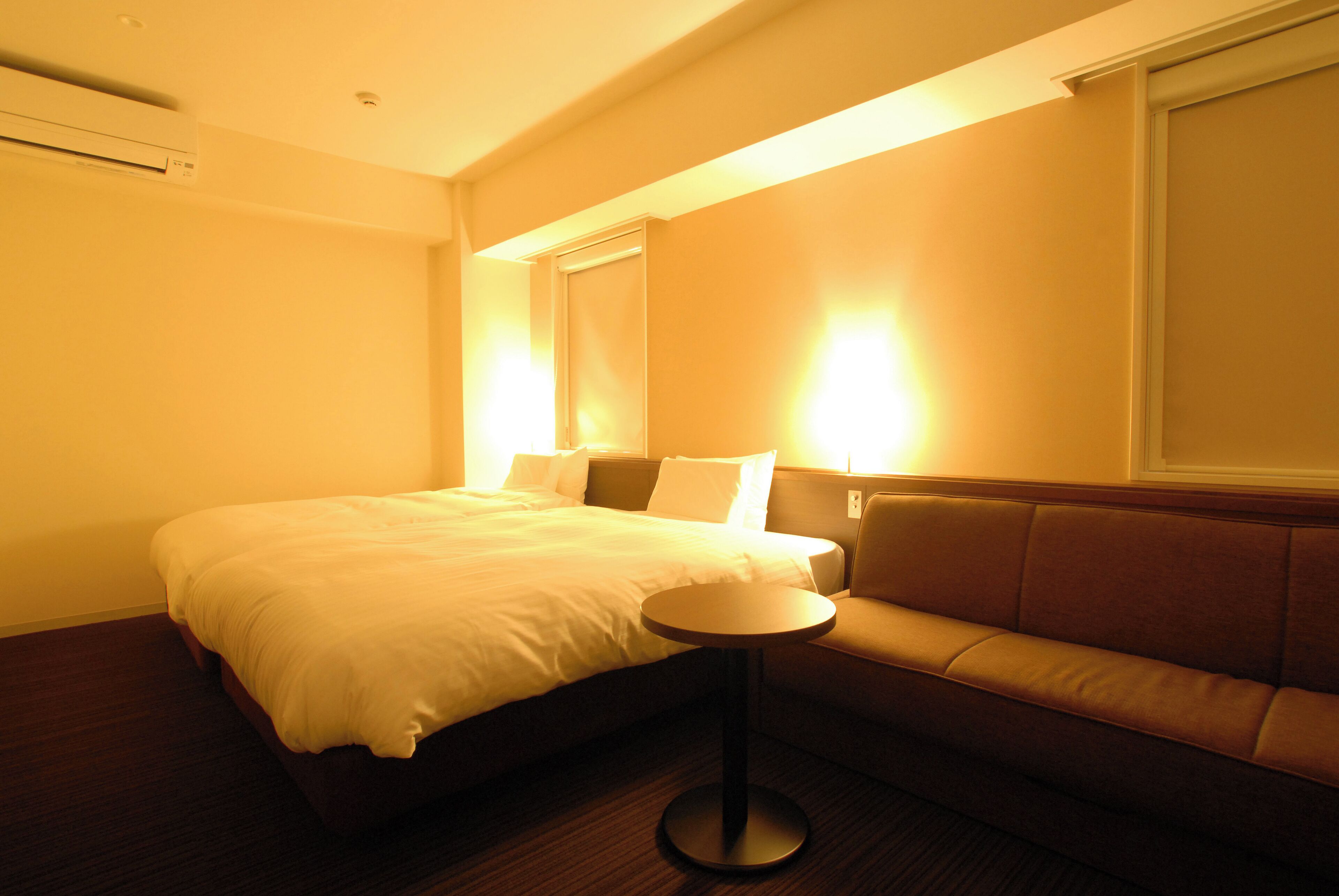 A hotel room with a bed, a small round table, and a sofa.