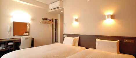 Una habitación de hotel con dos camas, un escritorio con silla, un espejo y luces en la pared.