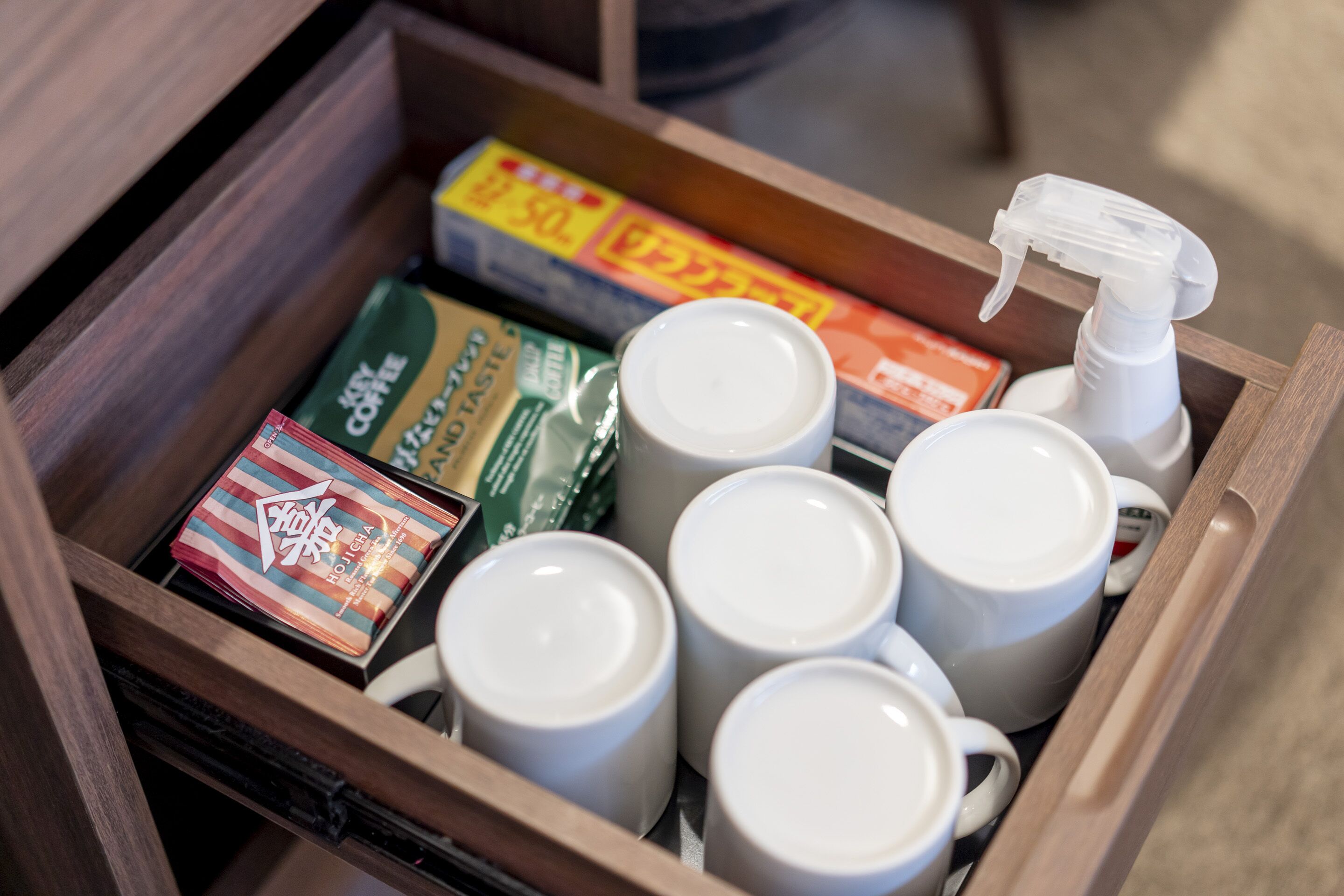 Een lade met koffiemokken, een spuitfles en koffieporties.