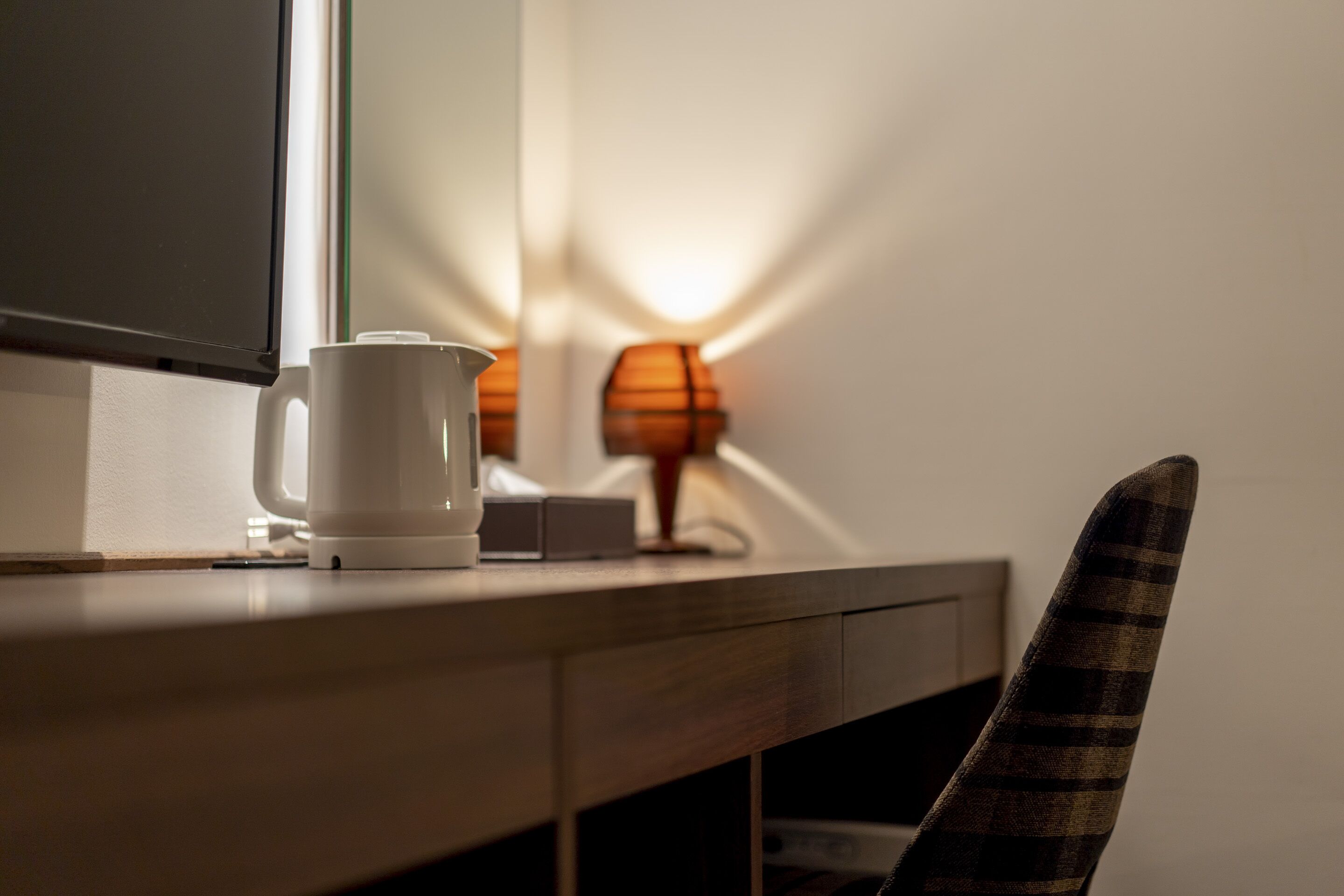 A desk with a white mug, a small box, and a lamp in the background.