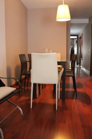 Un espace repas comprenant une table et des chaises, un luminaire suspendu et un plancher en bois.