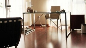 A modern living room with a glass coffee table, a black sofa, and a floor lamp.