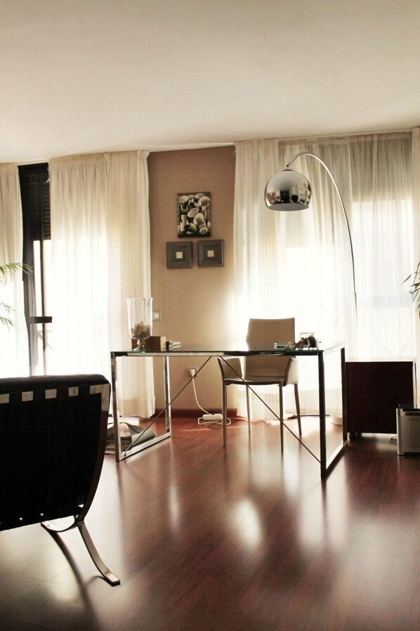 Una sala moderna con una mesa de centro de vidrio, un sofá negro y una lámpara de pie.