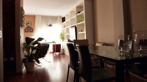 A dining area with a glass table, black chairs, and a potted plant.