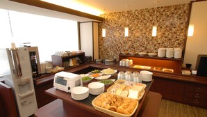 Una mesa de buffet con diversos alimentos, un microondas y un refrigerador.