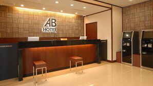 Zona de recepción de un hotel con diseño moderno, que incluye un mostrador, dos taburetes y una pared con diseño.
