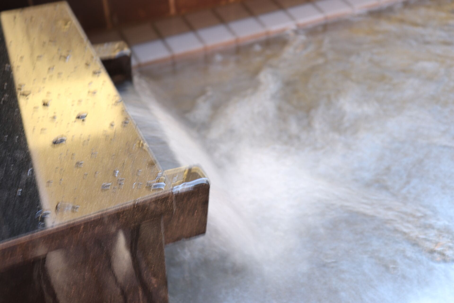 A close-up of a water feature with a wooden structure and a tiled floor.