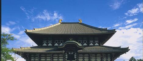 A traditional building with a symmetrical roof and multiple eaves, a central entrance, and a paved walkway leading to it.