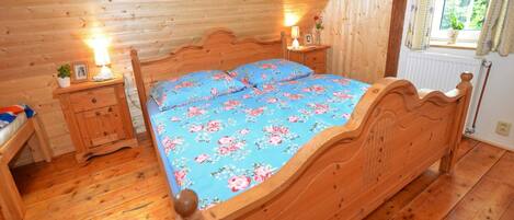 A wooden cabin bedroom with a bed, nightstands, and a window.