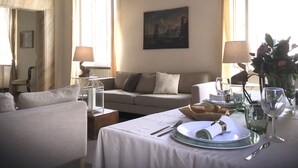 A dining area with a table set for two, a sofa, and a painting on the wall. - Rome, Historical Center, Via Giulia: unique, elegant, bright, 2 bedrooms, 2 bath (Roma)
