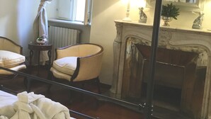 A bedroom with a bed, two chairs, a fireplace, and a mirror. - Rome, Historical Center, Via Giulia: unique, elegant, bright, 2 bedrooms, 2 bath (Roma)