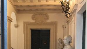A hallway with a dark door, a marble statue, and a staircase. - Rome, Historical Center, Via Giulia: unique, elegant, bright, 2 bedrooms, 2 bath (Roma)