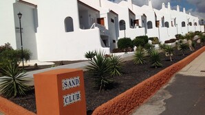 A row of white buildings with arched windows and a sign reading "SAND CLUB".