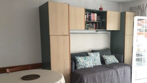A compact room with a bed, a small table, and a bookshelf.