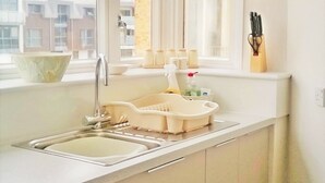 A modern kitchen with a large window, a sink, and a countertop with various items.