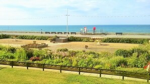 A landscaped garden with pathways, benches, and a view of the sea.