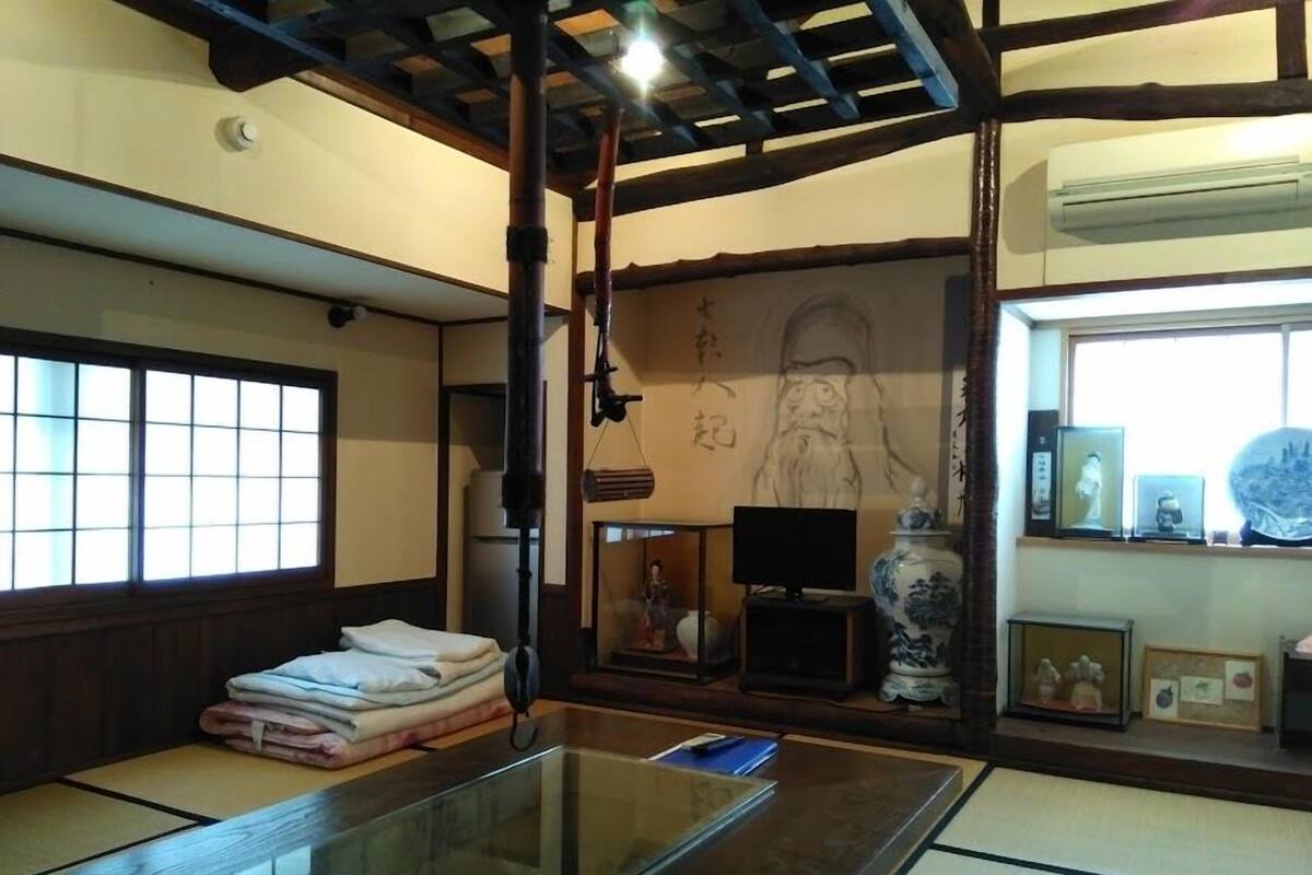 Une pièce de style japonais traditionnel, avec un sol recouvert de tatamis, une table en tatami, un paravent shoji, un rouleau suspendu et une grande œuvre calligraphique accrochée au mur.