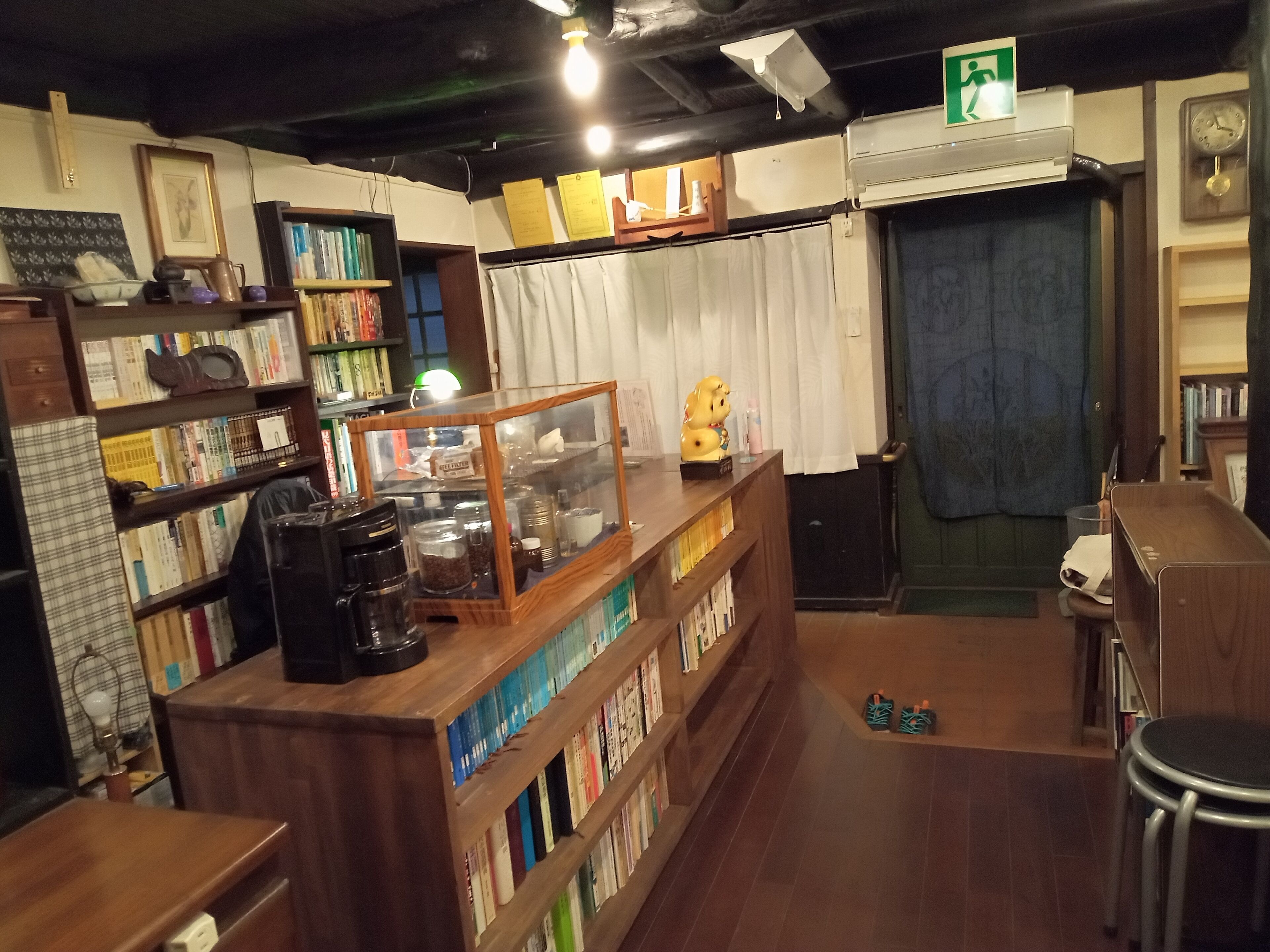 A cozy bookstore with wooden shelves, a coffee machine, and a display case.