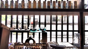 A room with a window overlooking a street, a shelf with decorative bottles, and a table with various items. - Guesthouse Arita (Arita)