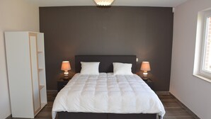 Un dormitorio con una cama grande, dos mesitas de noche con lámparas, un armario y una ventana.