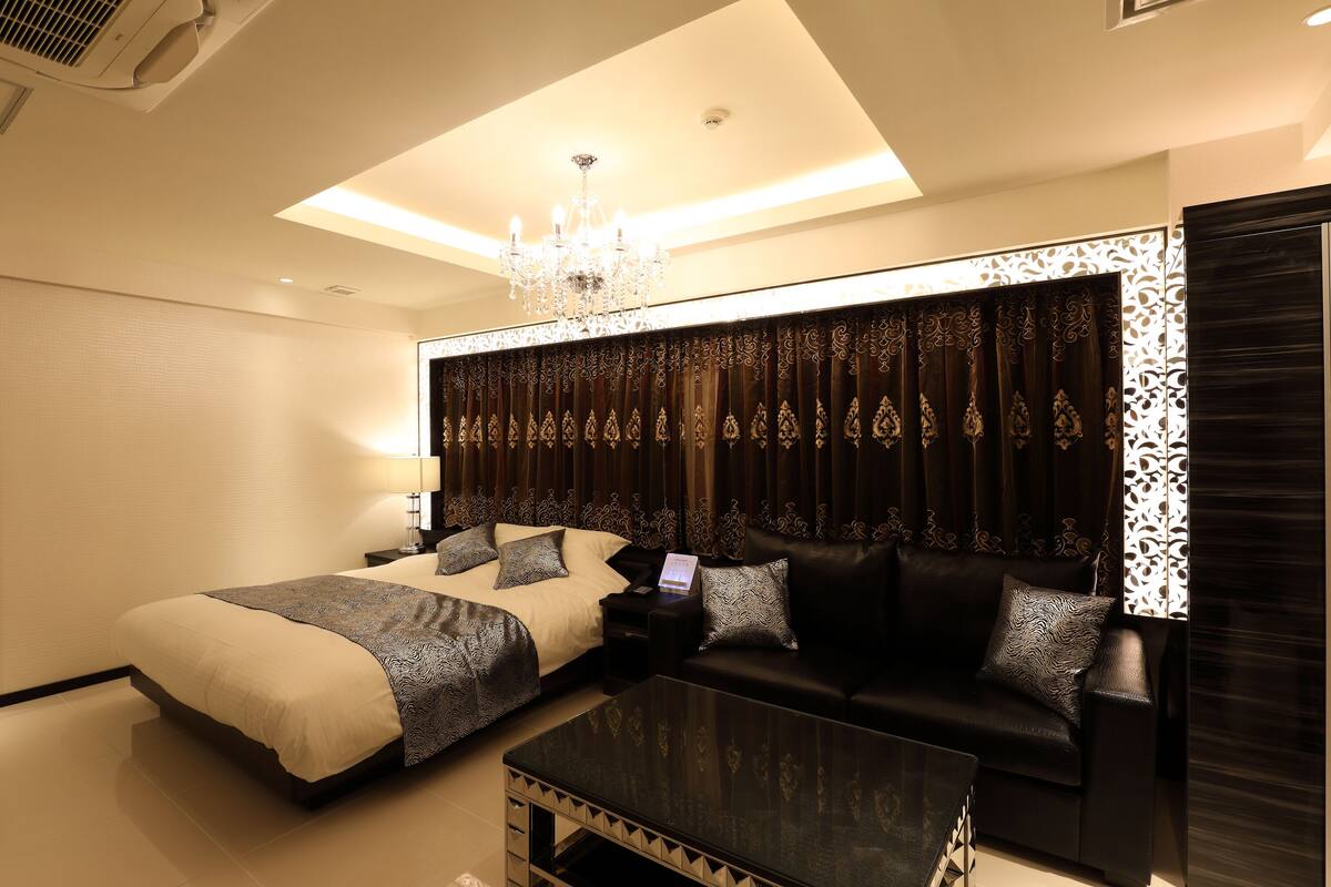 A hotel room with a bed, a sofa, a coffee table, and a chandelier.