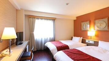 Una habitación de hotel con dos camas, un escritorio con lámpara, televisión y teléfono.