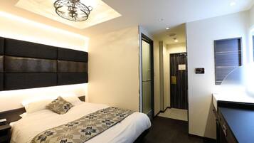 A modern hotel room with a large bed, a headboard, a bedside table, and a ceiling light fixture.