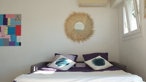 A bedroom with a bed, a wall-mounted mirror, and a geometric artwork.