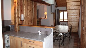 Een keuken met houten wanden, een granieten aanrecht en een eethoek met een tafel en stoelen.