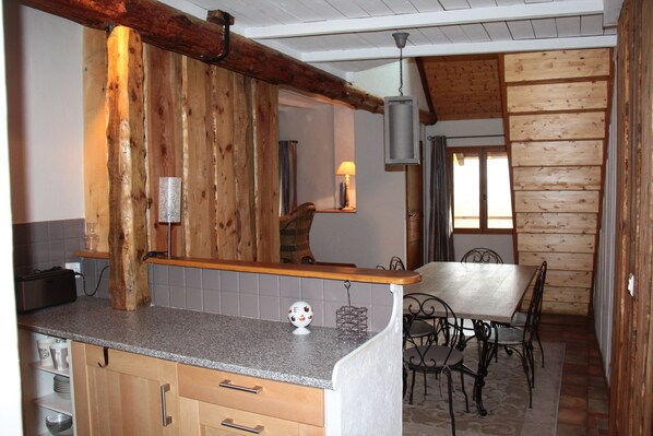 Una cocina con paredes de madera, encimera de granito y zona de comedor con mesa y sillas.