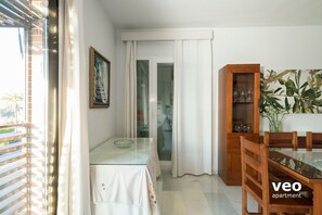 A dining area with a glass table, chairs, a cabinet with glassware, and a painting on the wall. - Torneo. 3 bedrooms, 2 bathrooms, free parking (Sevilla)